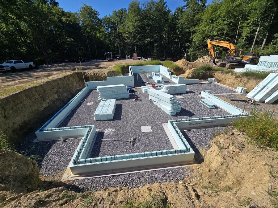 First course of Nudura insulated concrete forms set on the footing of a new foundation, with pallets of forms staged inside